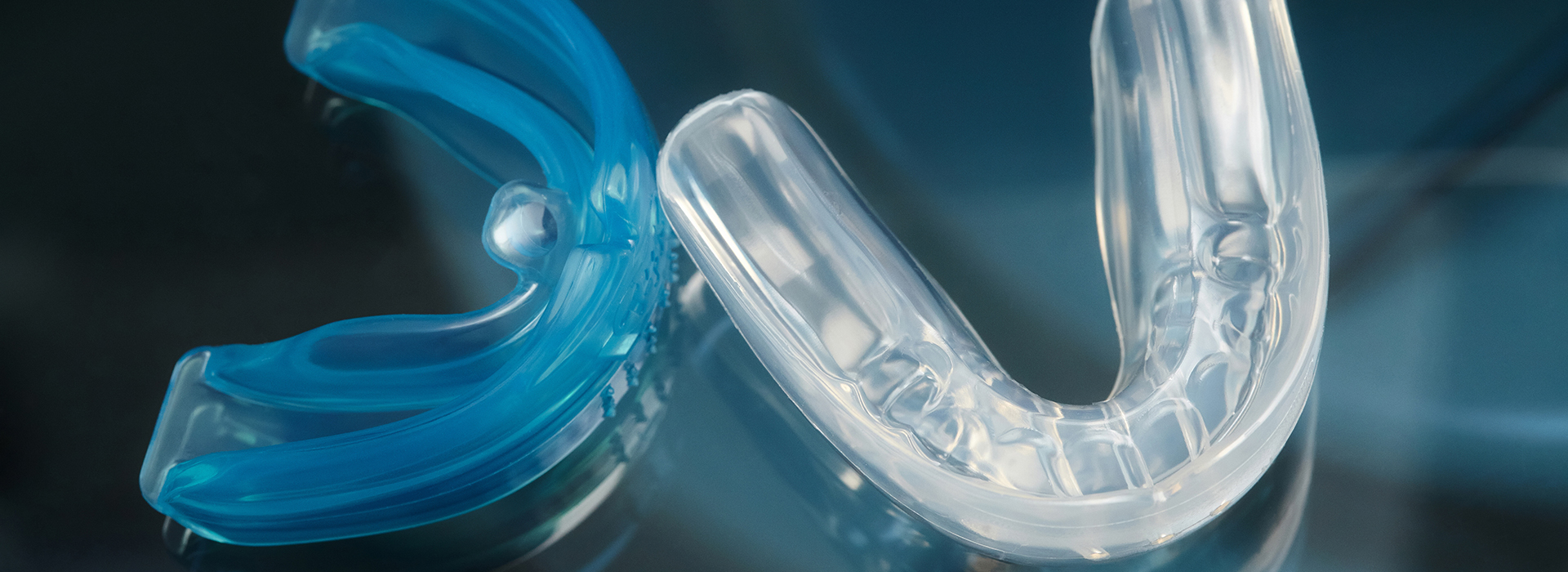 The image features a close-up view of a blue plastic object with a clear transparent center and an intricate design, which appears to be a piece of plastic or acrylic with a curved shape and possibly a handle or grip on one end.