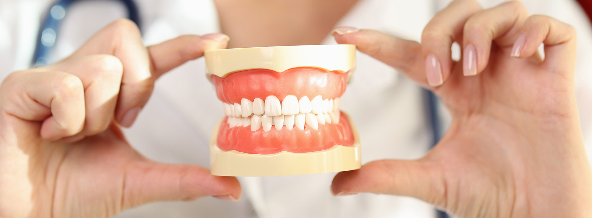 The image shows a person holding up their fingers to mimic teeth, with a focus on the lower front teeth being held together by the index finger.