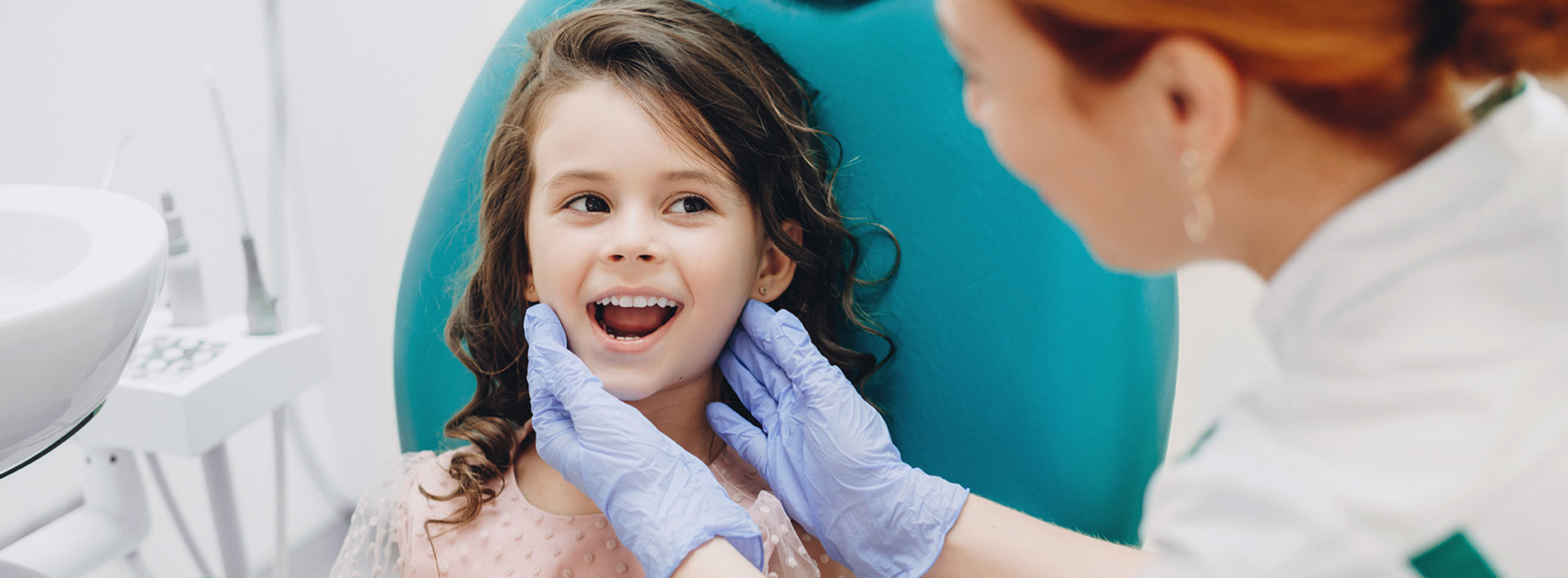 A young girl receiving dental care from a dentist wearing protective gloves.