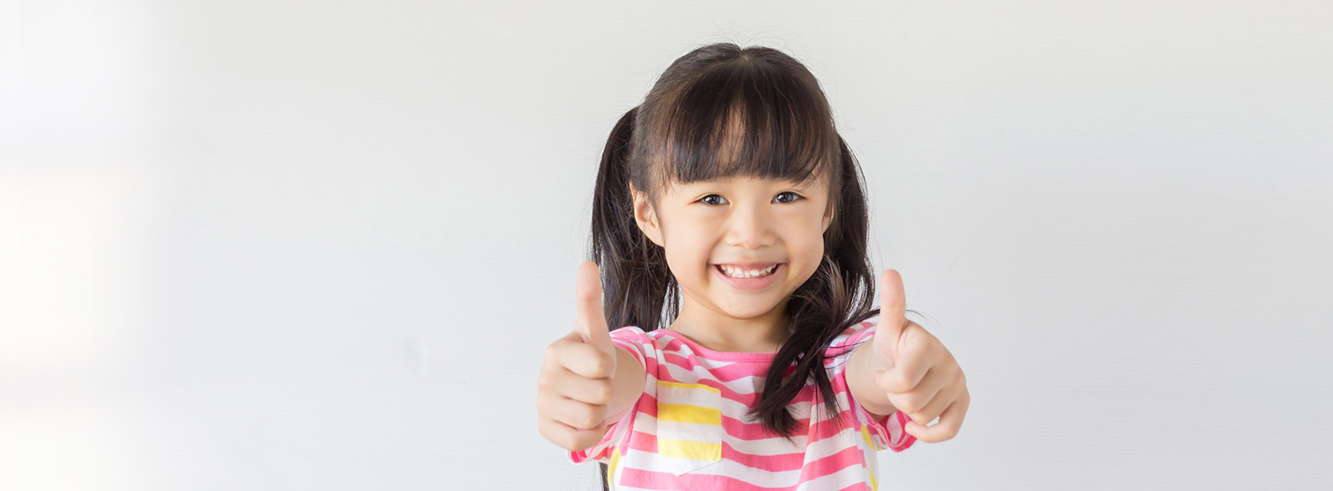 A young girl giving a thumbs-up sign against a white background.