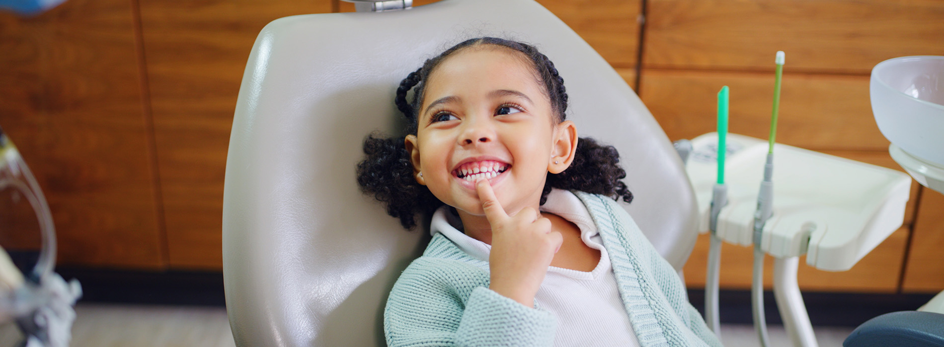 A young child sitting in a dental chair with a smile on their face.