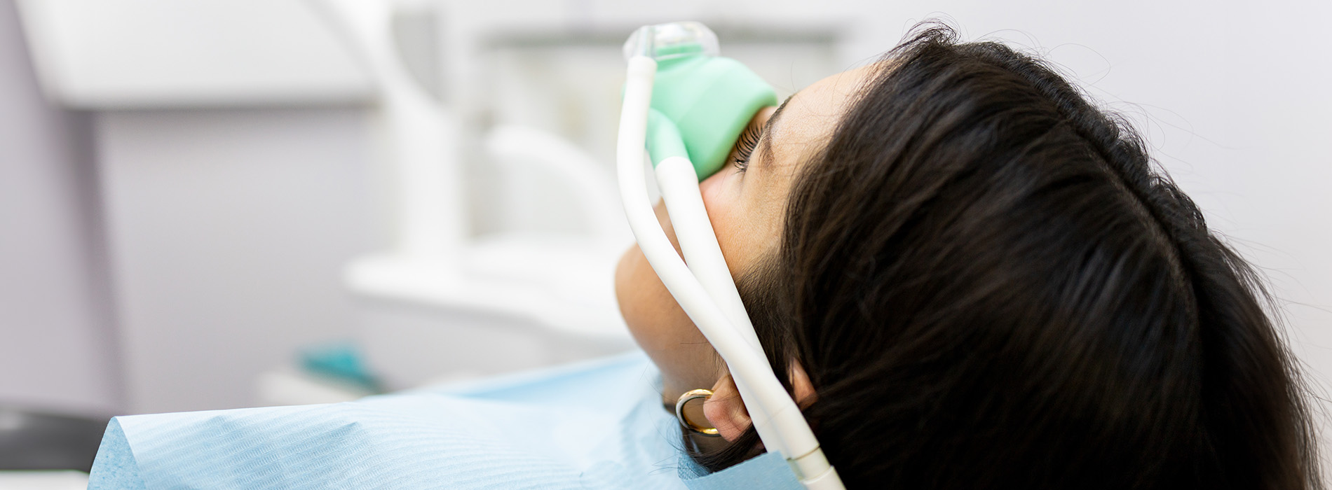 A person wearing a medical mask and intubation device, lying down with eyes closed, appears to be receiving oxygen therapy.