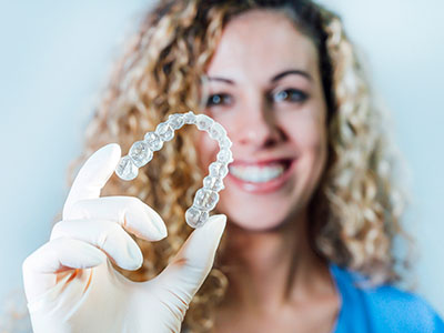 Woman holding up a clear plastic bag containing a row of clear gemstones, smiling.