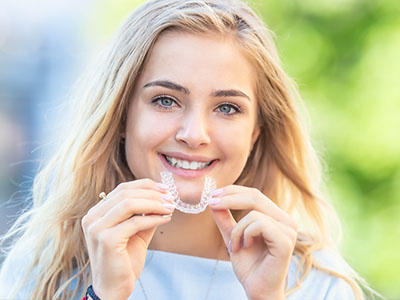 The image features a young woman with a radiant smile holding a toothbrush in her hand, showcasing a confident and healthy oral care routine.