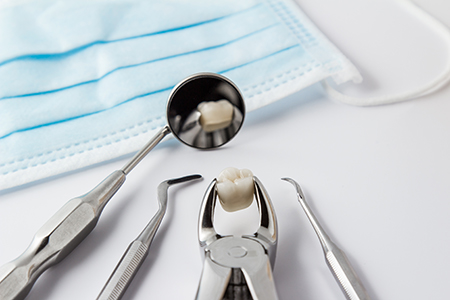The image shows a collection of dental tools including a toothbrush with a tooth on it, placed on a blue cloth, likely indicating oral hygiene or dental care.